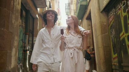 Fototapeta premium Cute man kissing woman nose outdoor. Young couple relaxing on old city street