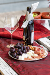 Fototapeta Wino czerwone i kieliszek .Talerz z prosciutto, serem brie i gorgonzolą, orzechami greckimi i winogronem. obraz