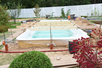 Fiberglass swimming pool construction building. Garden or backyard landscape works for swimming pool installation.