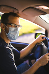 portrait of attractive nerd in long sleeve glasses and protective face mask in electric car at sunset