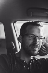 portrait of attractive nerd in long sleeve glasses and beard in the electric car at sunset