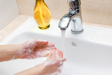 A Hands with soap are washed under the tap with water. Clean from infection and dirt and virus. At...