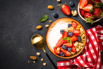 Greek yogurt granola with fresh berries on black stone table.