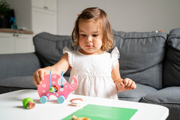 Naklejka premium Caucasian girl toddler playing with wooden elephant. Home schooling. independent play time