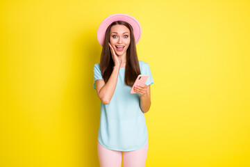 Photo crazy astonished girl blogging use smart phone impressed social media news touch hand face wear blue pink sunhat pants trousers isolated bright shine color background