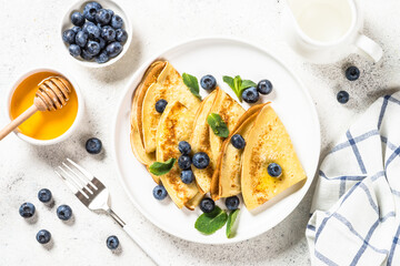 Crepes with blueberries at white table.