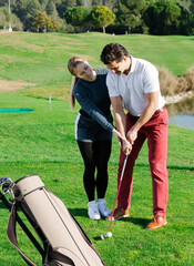 .Woman golfer teaches a young man the right to play golf
