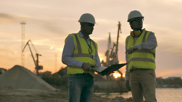 Loading port with two engineers having a discussion at sunset