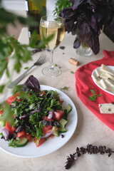 Vegetable and herb salad, sliced ​​cheese and a glass of wine.
