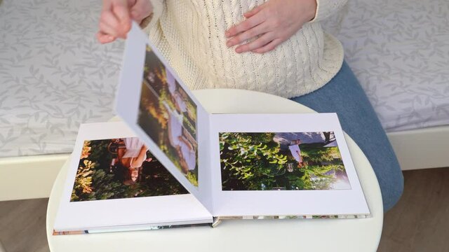 couple waiting for baby flips through photo book from family photo shoot.