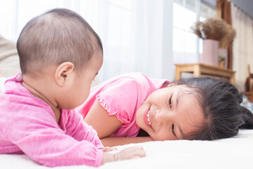 family with children at home. love, trust and tenderness..little sister hugging her newborn brother. toddler kid meeting new sibling. cute girl and new born baby boy relax in a white bedroom.