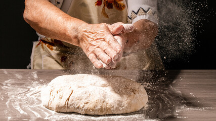 Photo of flour and women hands with flour splash. Cooking bread. Kneading the Dough. Isolated on dark background. Empty space for text