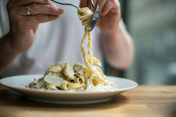 Selective focus shot of a male twirling delicious spaghetti on a fork