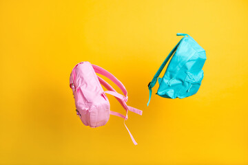Advert concept. Two school bags flight over yellow color background shopping center store mall offer low prices children accessory stuff