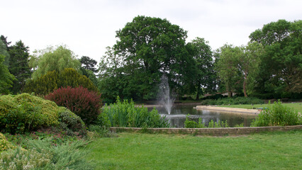 Park showing pond with fountain and copy space on grass below