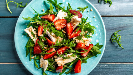 Close up salad with arugula, strawberries and cheese brie, camembert. Healthy food diet food concept. recipe background
