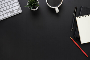 Top view above of Black office desk table with keyboard, notebook and coffee cup with equipment...