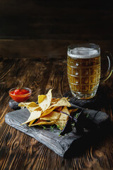 nachos on a wooden background with a beer mug. Copy of the space