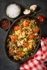 Baked meat with vegetables top view on black table.