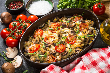 Baked meat with vegetables on black table.