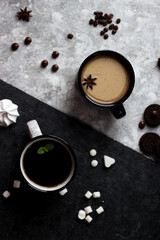 Black and white circles stand on a black and white background. Two cups, one with coffee, the other with tea on a black and white background
