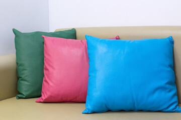 Colorful square leather pillow on brown sofa in living room , white wall background