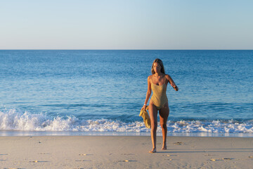 Real tanned girl along on beach walking.