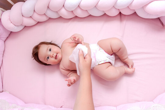 Newborn Baby Getting A Diaper Change: Mom Wiping Baby's Bottom With Baby Wipe. Emotions Of Newborn Baby