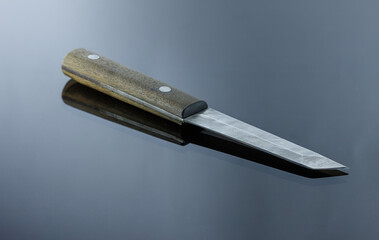 Japanese-style all-metal knife on a mirrored surface, handmade, damask blade, walnut handle