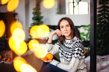Woman with a Christmas Gift on the Christmas interior background in bokeh lights garlands