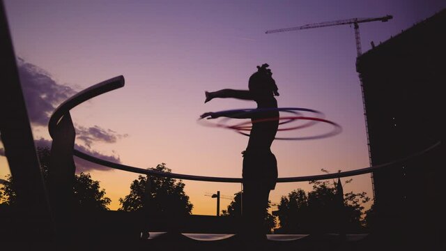 Sporty woman exercising with hula hoops during sunset