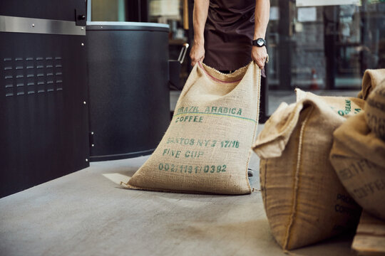 Male worker hands dragging bag with coffee beans