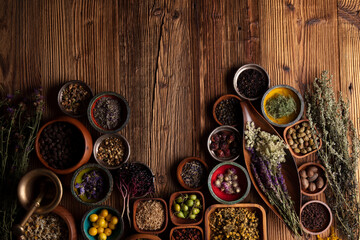 Natural medicine background. Assorted dry herbs in bowls and brass mortar on rustic wooden table.