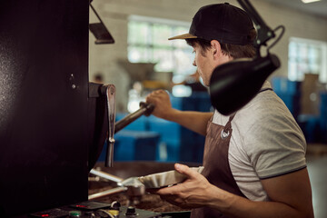 Male worker using industrial coffee roasting machine