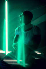 Hip-hop. Cinematic portrait of stylish young man in neon lighted room. Bright neoned colors. African-american model, musician indoors. Youth culture in party, festival style and music concept.