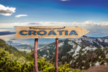 Croatia wooden arrow road sign against sea and mountains background. Travel to Croatia concept.