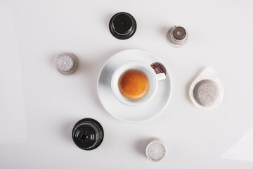 Tazzina con caffè fotografata dall'alto con capsule e cialde intorno a formare un cerchio