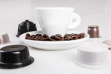 Tazzina bianca su cui apporre il logo con chicchi di caffè sul piattino e capsule intorno
