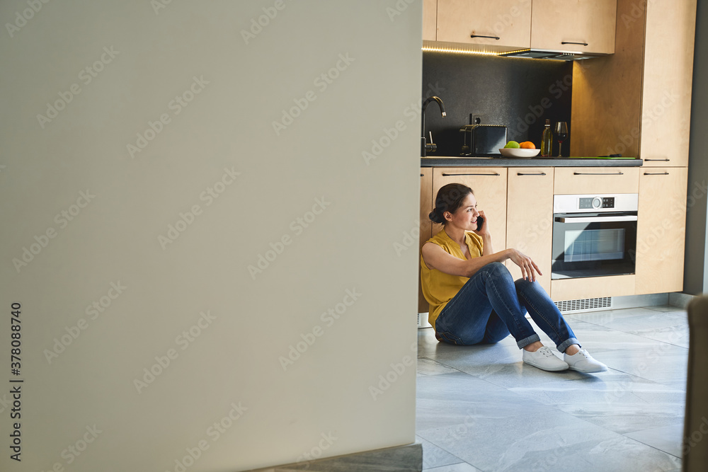 Wall mural Woman having a phone conversation in the kitchen