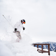 Winter kinds of sport concept. Skier wearing winter sports costume and ski equipment doing jumping tricks in winter season. Entertainments at ski resort in the mountains, side view
