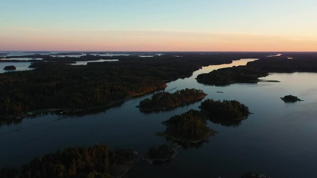 Aerial view of a boat, driving in middle of islands, moody, summer dusk, in the Swedish archipelago, at the Gulf of Bothnia, in Sweden - tracking, drone shot