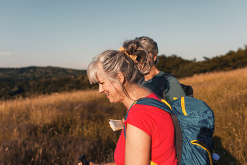 Active senior couple hiking in nature with backpacks, enjoying their adventure at sunset.	
