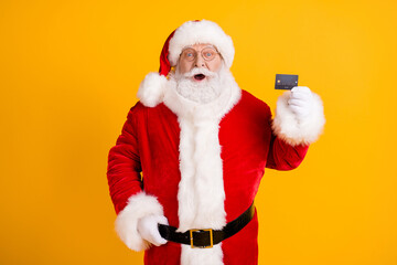 Photo astonished grey beard overweight santa claus impressed credit card payment x-mas christmas gift present discount buy wear cap headwear belt isolated bright shine color background