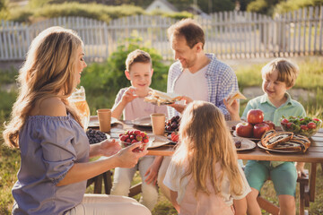 Positive family people mom dad little kids children sit table enjoy summer outside countryside meal...