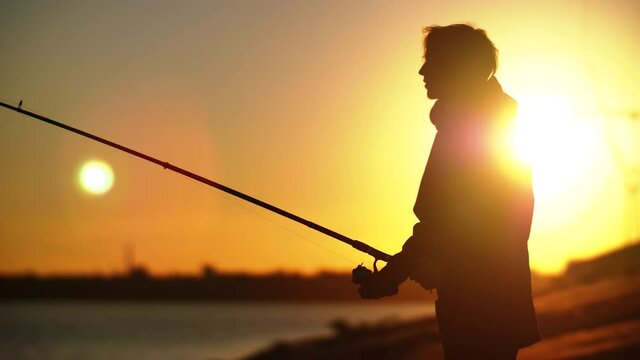Average fisherman's plan with fishing rod against sunset