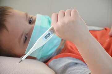 Sick Teenager with Thermometer in the Bed. fever, virus. waiting for a doctor. is treated at home. mom treats son