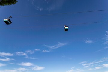 4k footage of the touristic cable car flying over the Tagus riverside in the city of Lisbon at sunset. Blue sky background with scattered clouds. Travel touristic concept lifestyle.