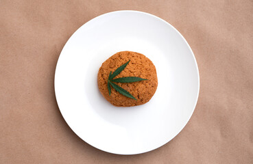Cannabis leaf with cookies on a white plate. Cannabis live resin extraction on kraft background. Medical marijuana concept