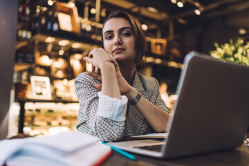 Thoughtful businesswoman with laptop working on project in cafe