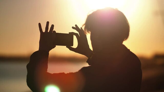 Silhouette of a man who shoots a landscape on the phone